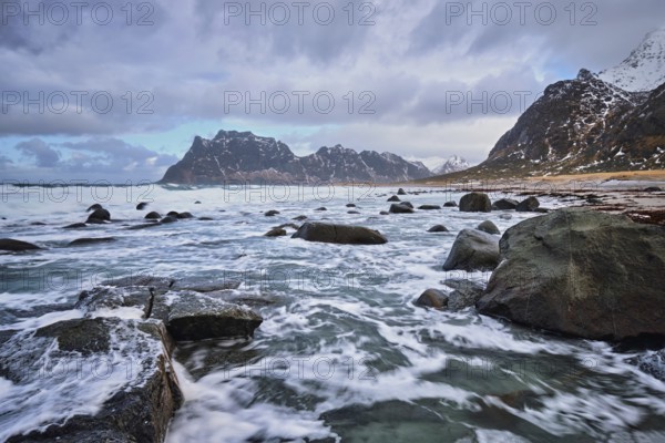 Rocks on beach of fjord of Norwegian sea in winter with snow. Utakliev beach, Lofoten islands, Norway, Europe