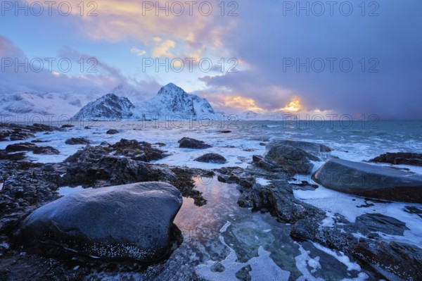 Beach of Norwegian sea on rocky coast in fjord on sunset in winter. Vareid beach, Lofoten islands, Norway, Europe