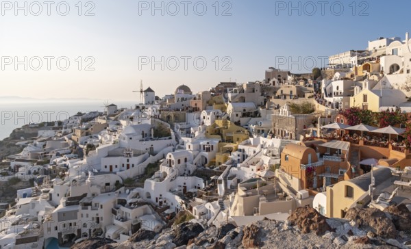 Cliff-side houses, villas and windmill in the village of Oia, Ia, as seen from the Kasteli Castle, Santorini, Greece, Europe