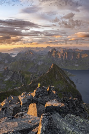 View over mountain peaks and sea, dramatic sunset, mountaineers at Hermannsdalstinden, with fjord Forsfjorden, Moskenesöy, Lofoten, Nordland, Norway, Europe