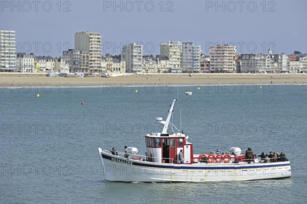 Fishing boat with sea anglers and apartments at Les Sables-d'Olonne, La Vendée, Pays de la Loire, France, Europe