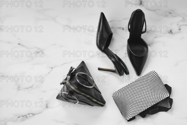 Overhead view of stilettos, fishnet tights and triangle hand bag on marble background