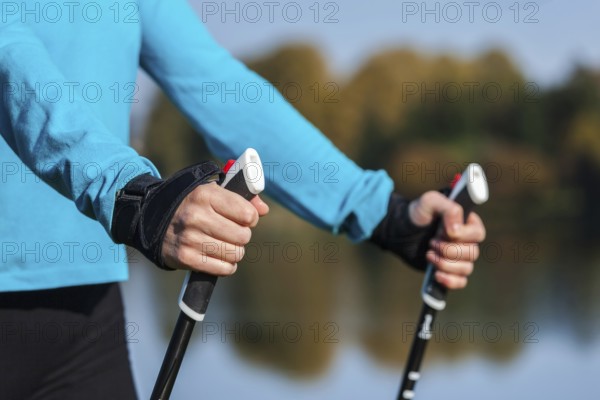 Nordic walking exercise adventure hiking concept, closeup of woman's hand holding nordic walking poles