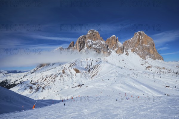 View of a ski resort piste with people skiing in Dolomites in Italy