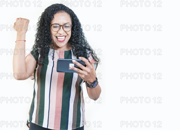 Excited young afro girl holding phone celebrating something. Happy afro woman holding smartphone and celebrating isolated