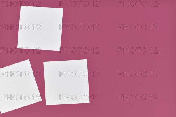 Three empty white paper notes on side of pink background with empty copy space