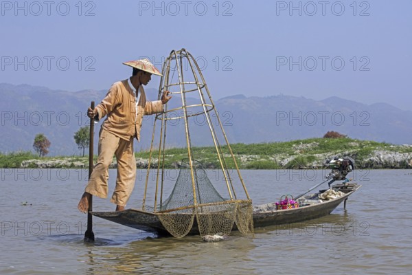 Intha fisherman steering traditional fishing boat by wrapping his leg around the oar, Inle Lake, Nyaungshwe, Shan State, Myanmar, Burma, Asia