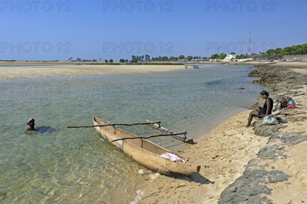 Single-outrigger canoe and two local Malagasy women on the beach at the coastal village Belo sur Mer, Morondava district, Menabe Region, Madagascar, Africa