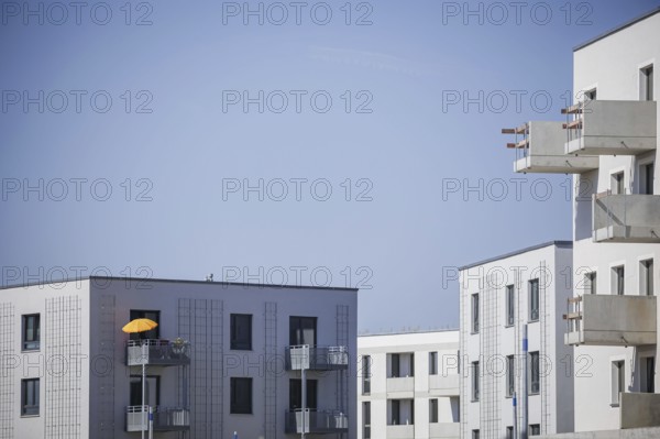 Symbolic photo on the subject of new housing construction. Buckower Felder neighbourhood on the southern outskirts of Berlin. Around 900 flats are being built on the 16-hectare site. A parasol stands on the balcony of a new-build flat that has already been occupied. Berlin, 29.08.2024