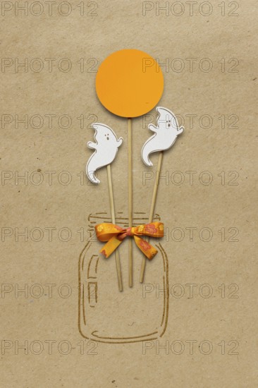 Creative Halloween concept photo of a bottle with ghosts made of paper on a brown background