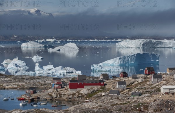 Large icebergs floating in fjord behind Inuit settlement Tiniteqilaaq, Sermilik Fjord, East Greenland, Greenland, North America