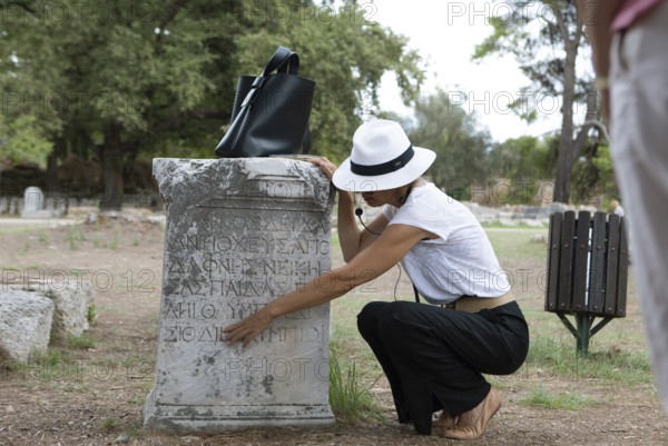 Woman explaining ancient inscriptions on a stone, archaeological site of Olympia, UNESCO World Heritage Site, Élis, Peloponnese, Greece, Europe