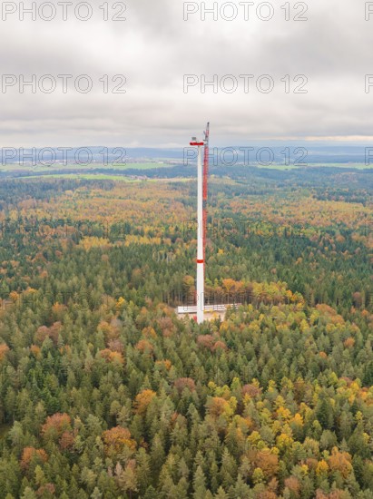 A tall wind power tower rises out of an autumn-coloured forest into the wide landscape, wind farm construction site, Grömbach, Black Forest, Germany, Europe