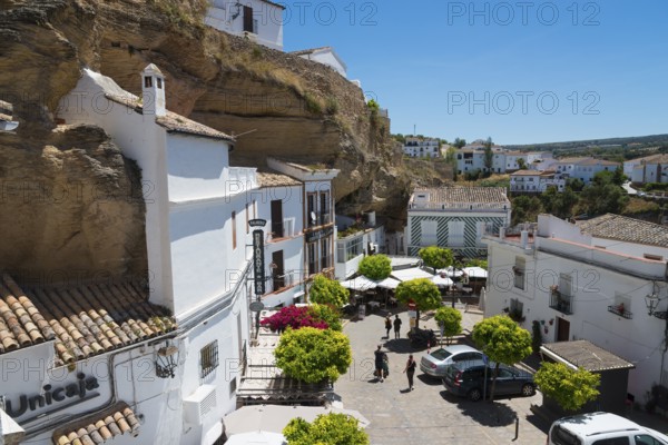 Square with cars and cafés in Setenil de las Bodegas under rocks with white houses, blue sky, cave dwellings, Setenil de las Bodegas, Cadiz, Andalusia, Spain, Europe