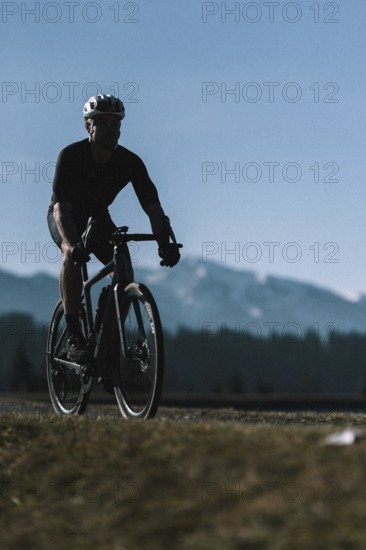 Road bike rider in spring in the Allgäu against the picturesque backdrop of the Alps, Bavaria, Germany, Europe