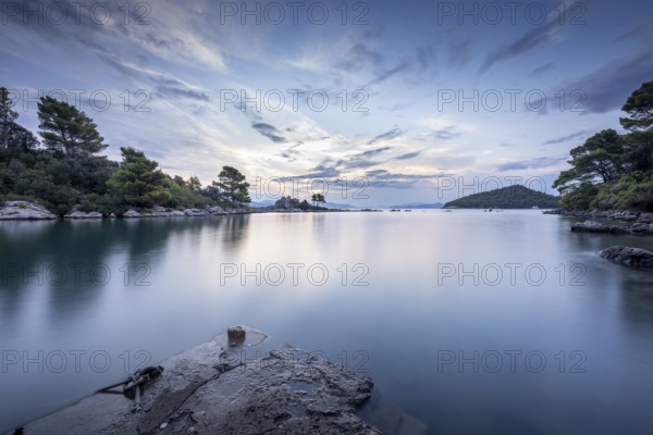 Calm sea at sunrise with cloudy sky and trees on the shore, Korcula, Neretva, Croatia, Europe