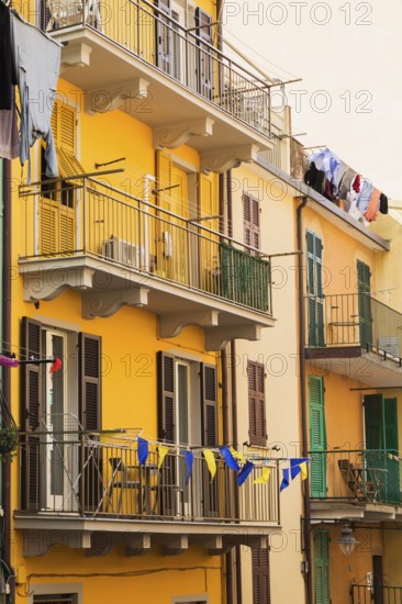 Yellow and beige stucco cladded residential apartment building facade and washed clothes drying on clothesline on balcony, Manarola, Cinque Terre, La Spezia province, Italy, Europe