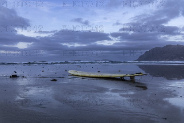 Lying surfboard on the beach with a view of the sea and an evening sky, Canary Islands, Lanzarote, Spain, Europe