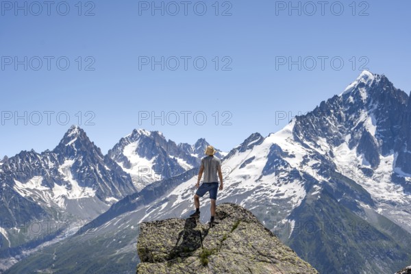 Mountaineer standing on a rock, mountain landscape with mountain peak Aiguille Verte, Mont Blanc massif, Aiguilles Rouges, Chamonix-Mont-Blanc, Haute-Savoie, France, Europe