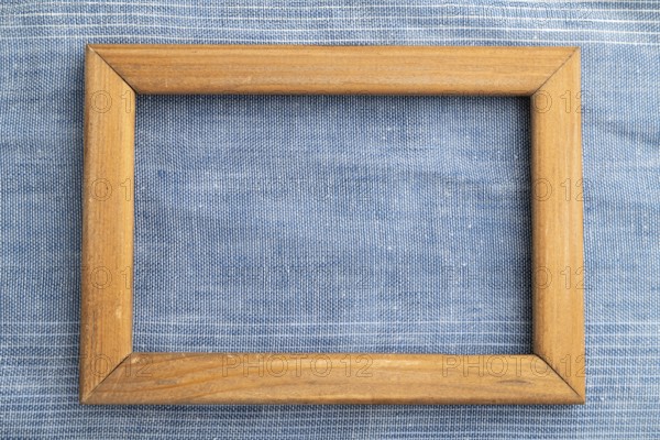 Wooden frame on smooth blue linen tissue. Top view, flat lay, natural textile background and texture