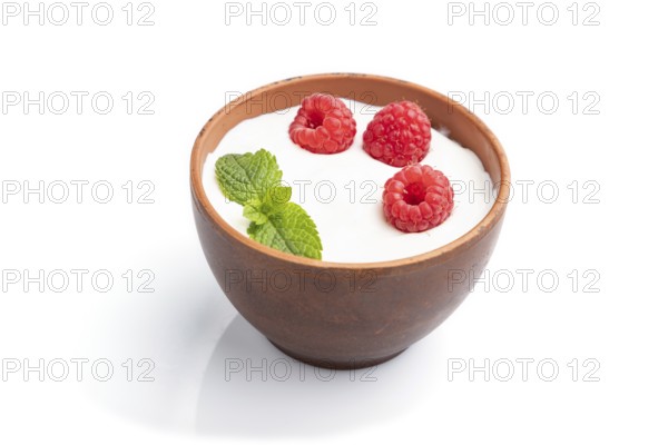 Yogurt with raspberry in clay cup isolated on white background. Side view, close up