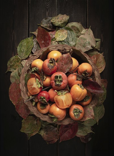 Fresh persimmon in a basket, with leaves, top view, no people