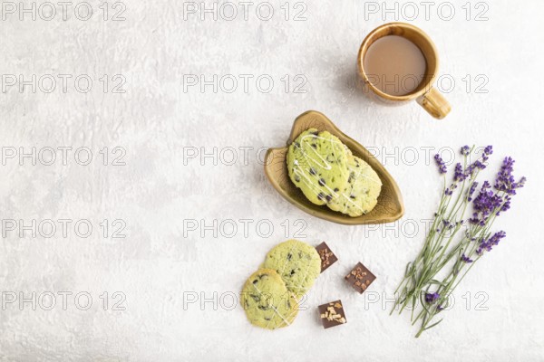 Green cookies with chocolate and mint on leaflike ceramic plate with cup of coffee on gray concrete background. top view, flat lay, copy space