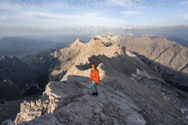 Mountaineer on a steep rocky ridge, impressive mountain landscape, view of the Höllental and the Alpspitze from the Jubiläumsgrat, in the evening light Zugspitze, Wetterstein range, Bavaria, Germany, Europe