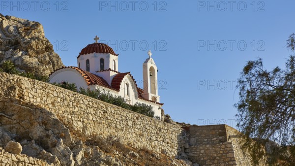 White church with red roofs on a rock, surrounded by nature under a clear blue sky, Panormitis Church, Pigadia, town and harbour, Pigadia Bay, main town, Karpathos, Dodecanese, Greek Islands, Greece, Europe