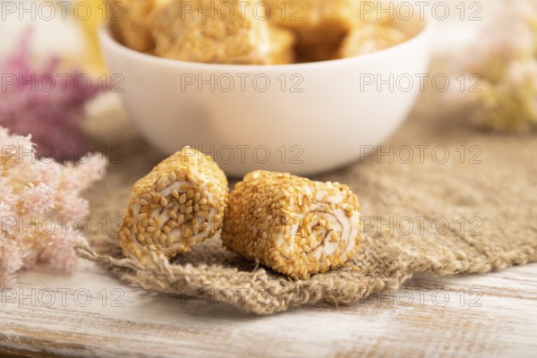 Traditional turkish delight (rahat lokum) in white ceramic plate with glass of green tea on a white wooden background. side view, close up, selective focus