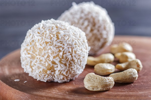 Energy balls cakes with coconut and cashew on wooden board on black background. selective focus, close up