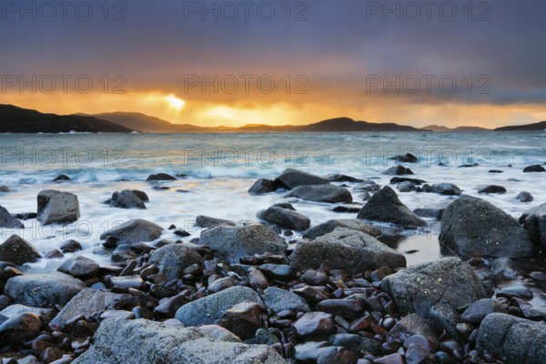 Atmospheric coloured cloudy sky at sunrise on a rocky beach near Reiff on the west coast of Scotland