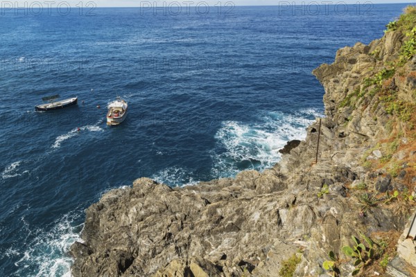 Rocky cliff and fishing boats moored in bay, Ligurian Sea, Manarola village in late summer, Cinque Terre, La Spezia province, Italy, Europe