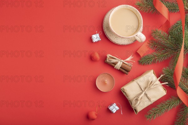 Christmas or New Year composition. Decorations, box, cinnamon, fir and spruce branches, cup of coffee, on a red paper background. Top view, copy space, flat lay