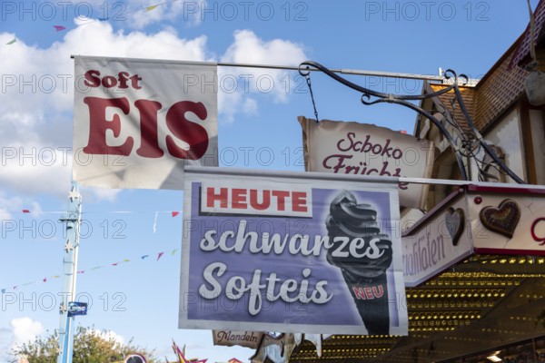 Advertising sign for black soft ice cream on a fairground with blue sky in the background, Magdeburg, Saxony-Anhalt, Germany, Europe