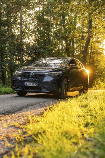 Car on forest road with setting sun in the background, harmonious atmosphere, electric car, VW ID5, Gechingen, Black Forest, Germany, Europe