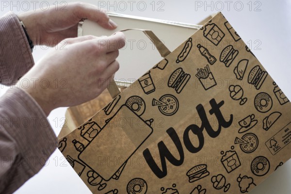 A person takes an order from a paper bag from the delivery service Wolt. Berlin, 28.03.2024