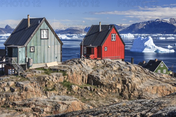 Typical Greenlandic houses in front of icebergs, Inuit settlement, summer, sunny, Uummannaq, West Greenland, Greenland, North America