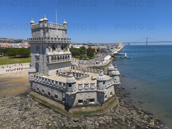 A tower on a riverbank with a bridge in the background and a clear blue sky, aerial view, Torre de Belém, World Heritage Site, Belem, Bethlehem, Lisbon, Lisboa, River Tagus, Portugal, Europe