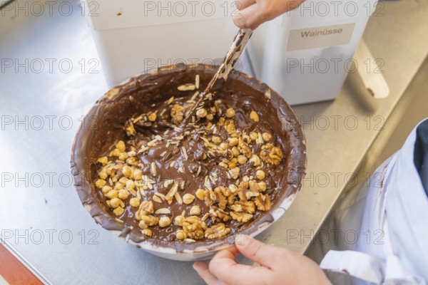 Mixing nuts in a bowl filled with chocolate, Burch Schokolade production, Haselstaller Hof, Gechingen, Germany, Europe