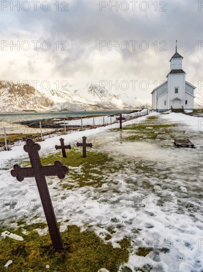 Gimsøy church with cemetery, snow-covered mountains in the background, winter, Gimsøya, Lofoten, Norway, Europe