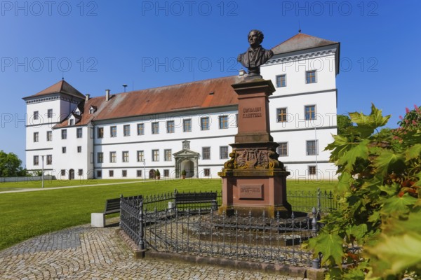 Monument in honour of Conradin Kreutzer, musician, conductor and composer, bust of Hans Baur, sculptor, sculpture, pedestal, writing, letters, public art, statue, behind Meßkirch Castle, Castle of the Counts of Zimmern, Zimmern Castle, regular four-wing castle complex, Renaissance building, architecture, historical building, park, castle garden, fence, blue sky, cloudless, Meßkirch, Sigmaringen district, Baden-Württemberg. Germany