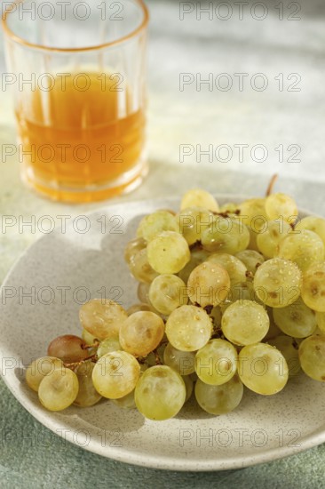 A branch of white grapes, on a gray plate, with a glass of white wine, top view, natural light, food concept, no people