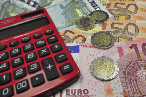 Euro banknotes and coins and pocket calculator