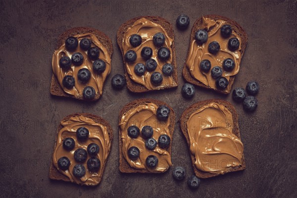 Rye bread with peanut paste and fresh blueberries, top view, no people