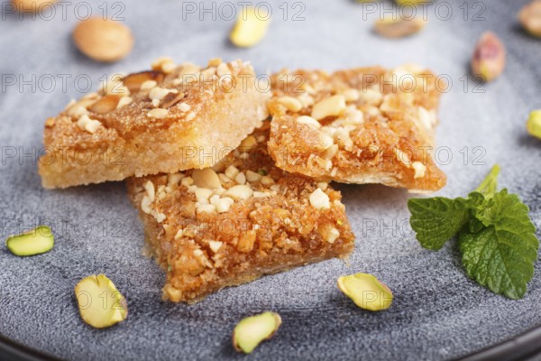 Traditional arabic sweets in gray ceramic plate on a gray concrete background. side view, close up, selective focus