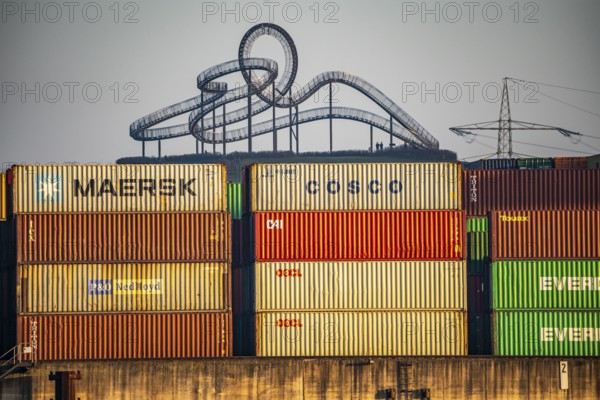 Container Handling Centre, Gateway West Terminal, Logport 2, cargo ship, in Duisburg on the Rhine, in the background Tiger and Turtle - Magic Mountain is a landmark modelled on a roller coaster on Heinrich-Hildebrand-Höhe in Angerpark in Duisburg-Angerhausen, North Rhine-Westphalia, Germany, Europe