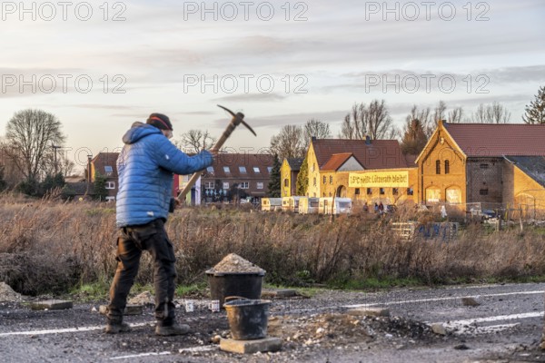 Climate activists chop up the asphalt of a road to erect obstacles, barricades, to prevent the police from evicting the occupied hamlet of Lützerath, the remains of the village are to make way for lignite mining, an eviction is imminent, North Rhine-Westphalia, Germany, Europe