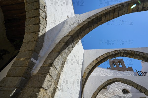 Stone arch and bell tower on a sunny day, Part of a medieval monastery with white walls, Inside the monastery, Agiou Theologou Monastery, Chora, Patmos, Dodecanese, Greek Islands, Greece, Europe