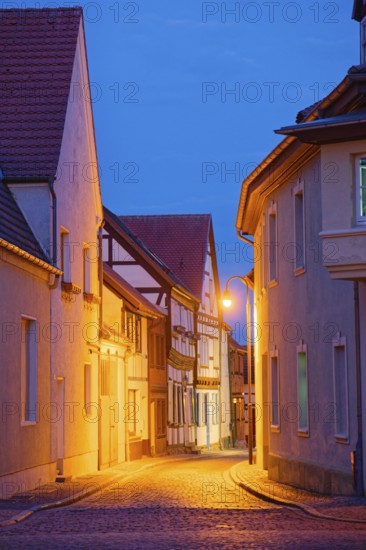 The Kleine Fischerstraße with half-timbered houses and other old buildings, covered with cobblestones, illuminated in the evening. Old town centre of Tangermünde, Hanseatic town in the Altmark. Saxony-Anhalt, Germany, Europe